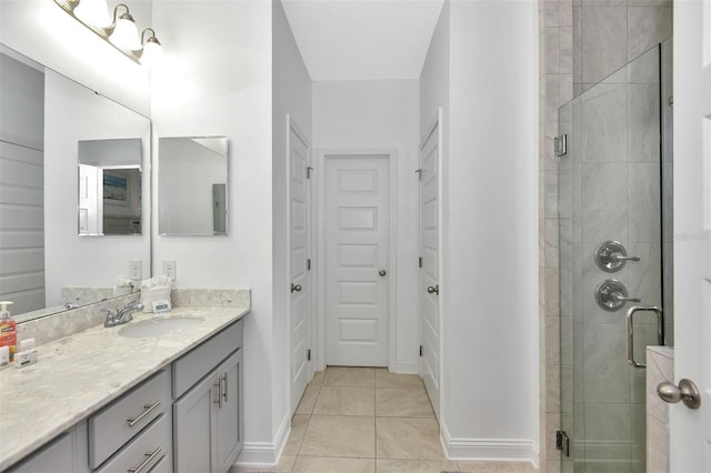 bathroom featuring tile patterned floors, vanity, a stall shower, and baseboards