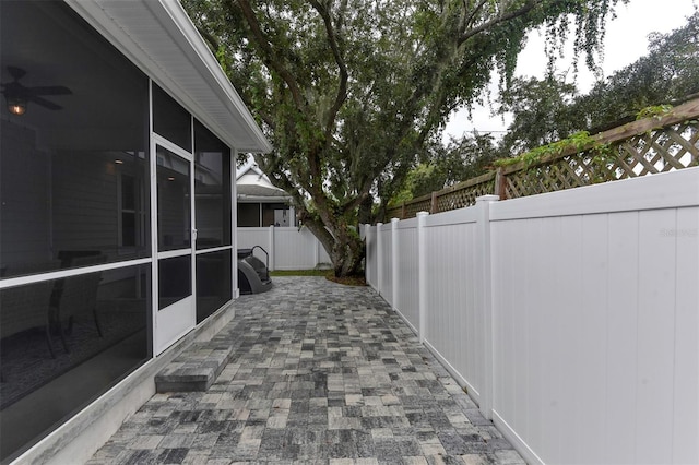 view of patio / terrace featuring a sunroom, a fenced backyard, and a ceiling fan