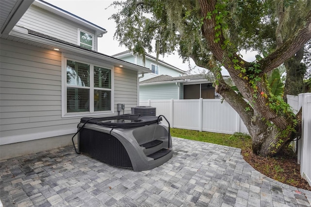view of patio / terrace featuring a hot tub, fence, and central air condition unit