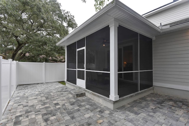 view of side of property with a sunroom, fence, and a patio