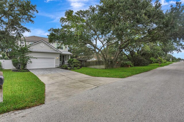 traditional-style home with a front yard, driveway, fence, and an attached garage