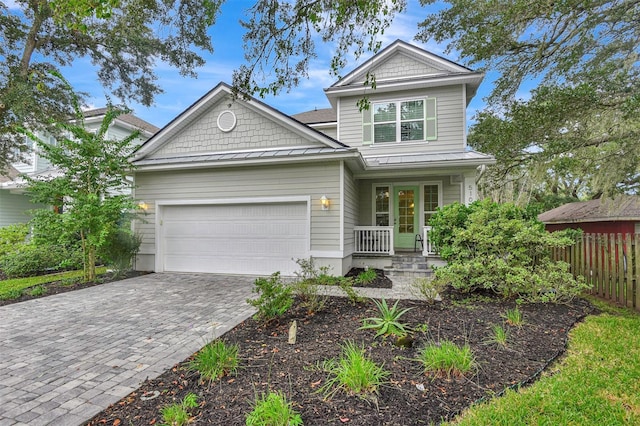craftsman-style house featuring covered porch, a garage, fence, and decorative driveway