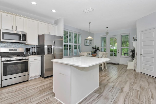 kitchen with decorative backsplash, light countertops, visible vents, appliances with stainless steel finishes, and pendant lighting