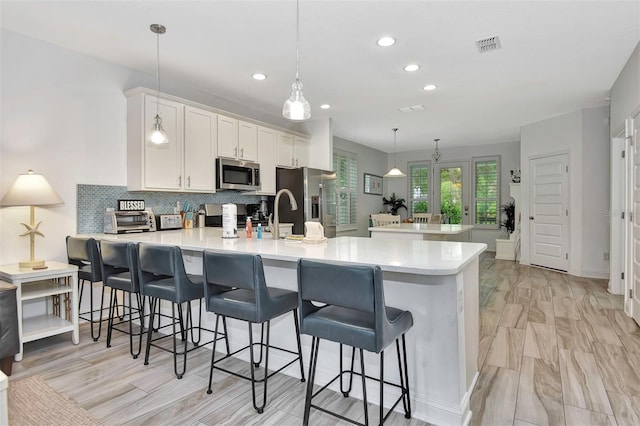 kitchen featuring a breakfast bar area, tasteful backsplash, a peninsula, and stainless steel appliances