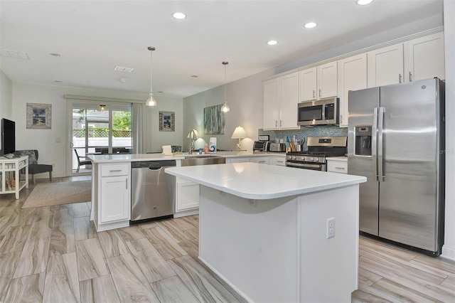 kitchen with white cabinets, a sink, stainless steel appliances, and a peninsula