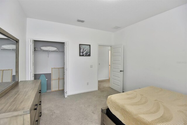 bedroom with baseboards, visible vents, a closet, and light carpet