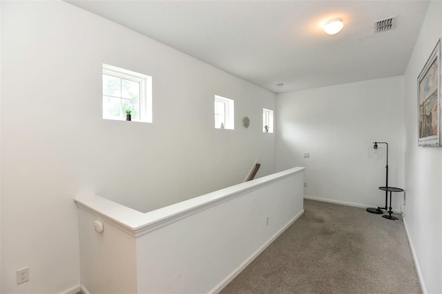 corridor with an upstairs landing, carpet, baseboards, and visible vents