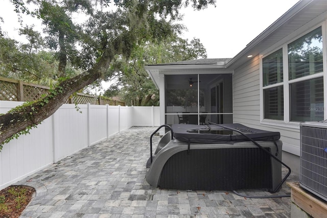 view of patio with cooling unit, a fenced backyard, a sunroom, and a hot tub