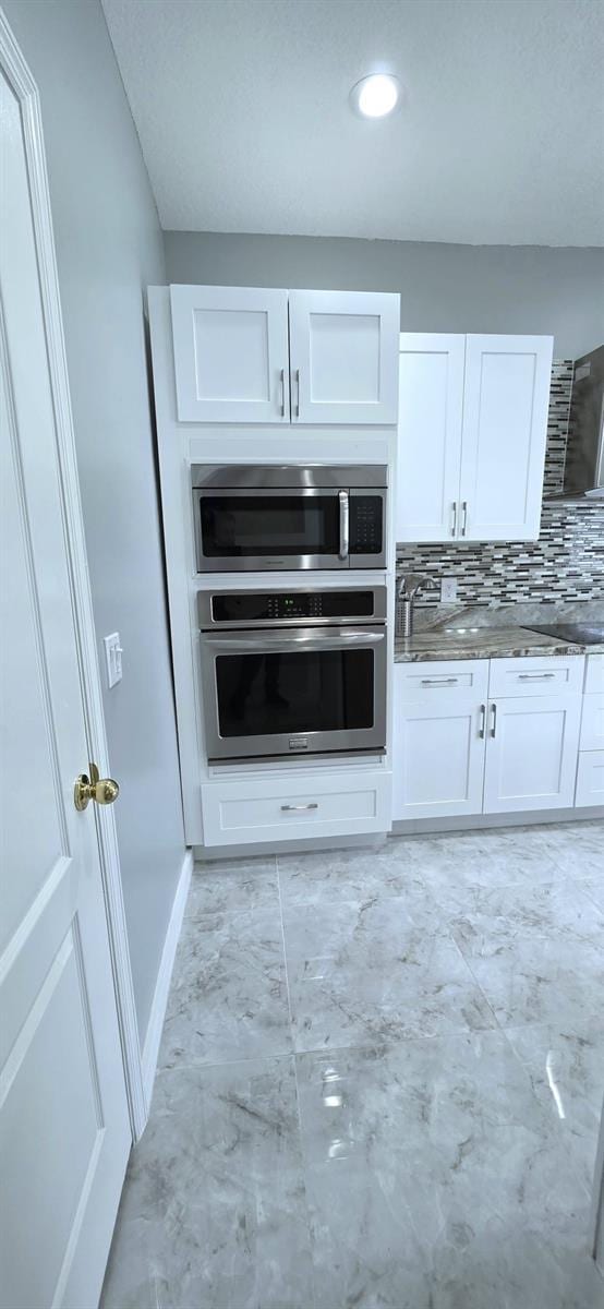 4730 Capital Blvd, Saint Cloud, FL 34769 - kitchen with white cabinets, marble finish floor, stainless steel appliances, tasteful backsplash, and stone countertops