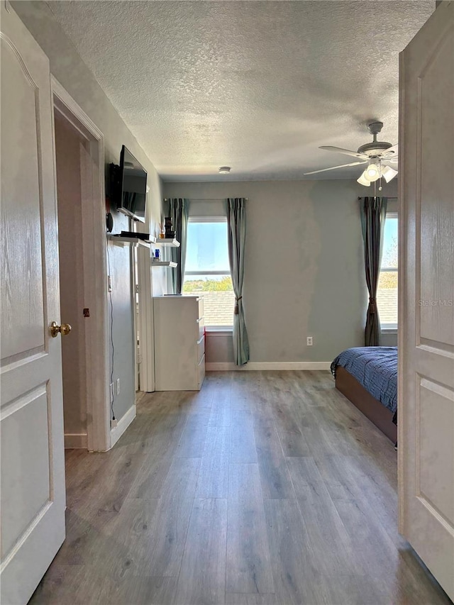 4730 Capital Blvd, Saint Cloud, FL 34769 - unfurnished bedroom featuring baseboards, a textured ceiling, wood finished floors, and a ceiling fan