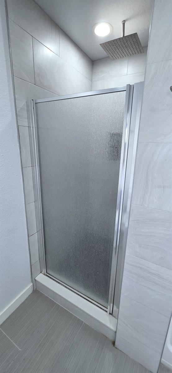 4730 Capital Blvd, Saint Cloud, FL 34769 - full bathroom featuring baseboards, tile patterned floors, and a shower stall