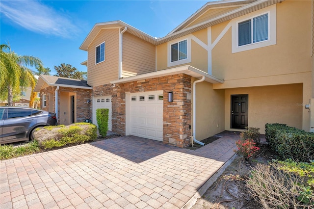 10124 Shadow Leaf Ct, Orlando, FL 32825 - view of property featuring stone siding, a garage, stucco siding, and decorative driveway
