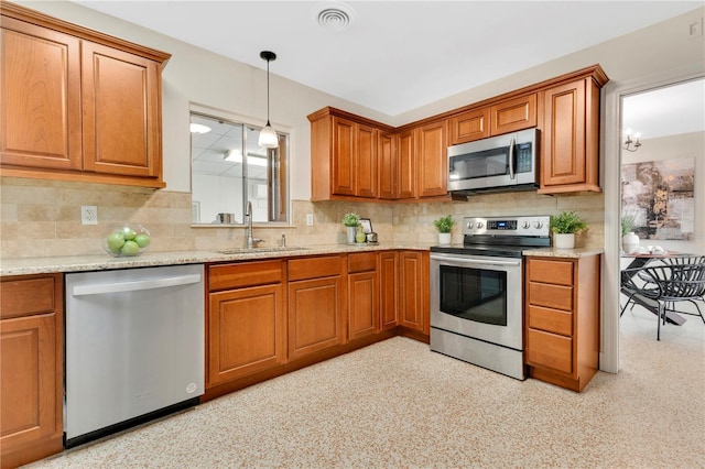 3107 Troy Dr, Orlando, FL 32806 - kitchen featuring light stone countertops, appliances with stainless steel finishes, a sink, brown cabinets, and decorative backsplash