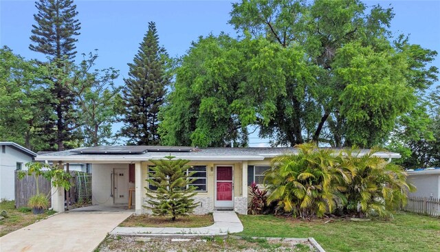 6031 W Ridgewood Ave, Orlando, FL 32835 - view of front of home featuring concrete driveway, solar panels, an attached carport, and stone siding