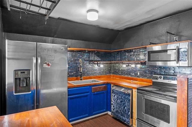 6031 W Ridgewood Ave, Orlando, FL 32835 - kitchen featuring stainless steel appliances, butcher block countertops, dark wood-style floors, blue cabinetry, and vaulted ceiling