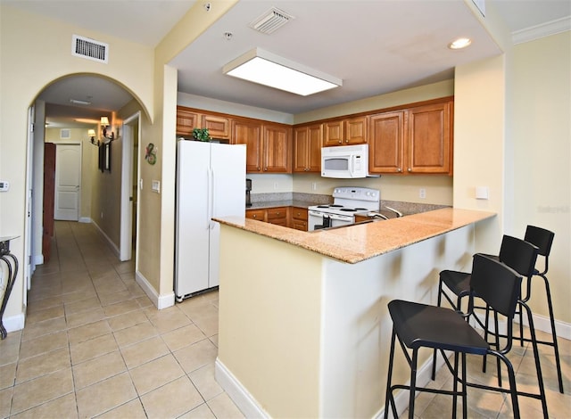 13427 Blue Heron Beach Dr Unit 1802, Orlando, FL 32821 - kitchen featuring visible vents, a peninsula, white appliances, a kitchen bar, and light tile patterned floors
