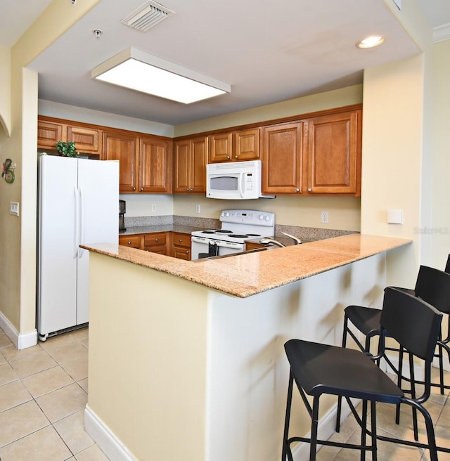 13427 Blue Heron Beach Dr Unit 1802, Orlando, FL 32821 - kitchen featuring light tile patterned flooring, visible vents, brown cabinets, and white appliances