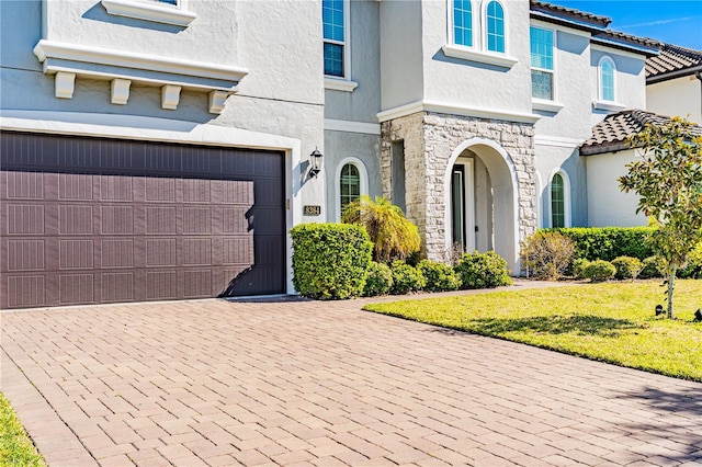 8384 Ludington Cir, Orlando, FL 32836 - view of front of house with stucco siding, an attached garage, stone siding, decorative driveway, and a front yard