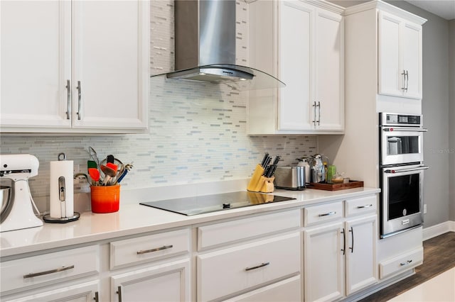 8384 Ludington Cir, Orlando, FL 32836 - kitchen with wall chimney exhaust hood, stainless steel double oven, black electric cooktop, white cabinets, and decorative backsplash