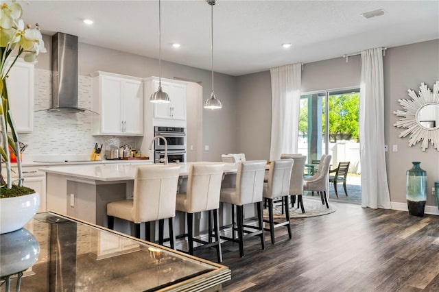 8384 Ludington Cir, Orlando, FL 32836 - kitchen featuring decorative backsplash, dark wood-style flooring, a kitchen island with sink, wall chimney exhaust hood, and electric cooktop