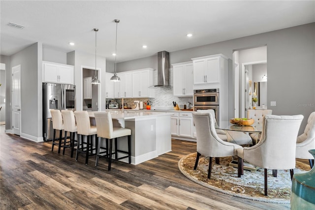 8384 Ludington Cir, Orlando, FL 32836 - kitchen featuring dark wood-style flooring, visible vents, wall chimney exhaust hood, a center island with sink, and appliances with stainless steel finishes