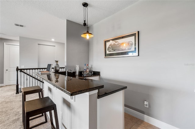 8384 Ludington Cir, Orlando, FL 32836 - kitchen featuring light tile patterned flooring, a kitchen bar, a textured ceiling, visible vents, and dark stone counters