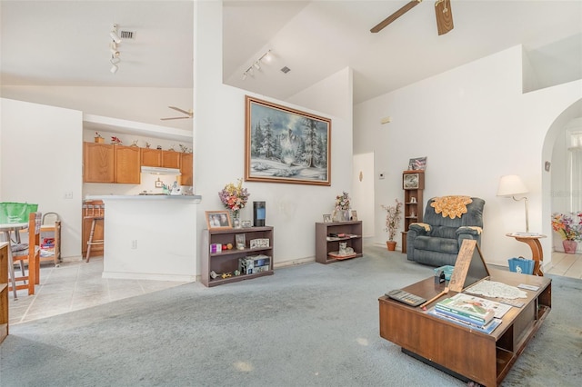 living room featuring visible vents, rail lighting, a ceiling fan, arched walkways, and light colored carpet