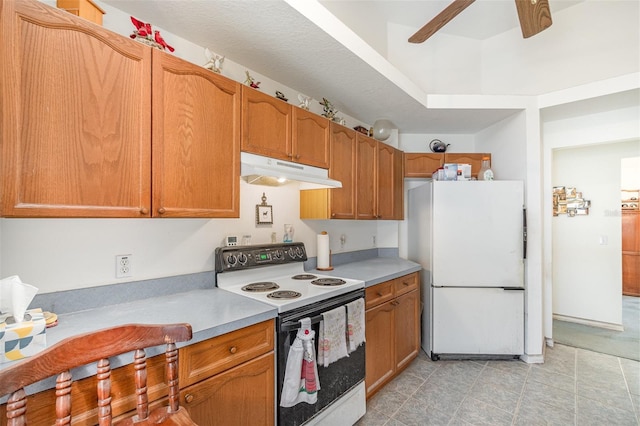 kitchen featuring light countertops, white appliances, under cabinet range hood, a ceiling fan, and brown cabinetry