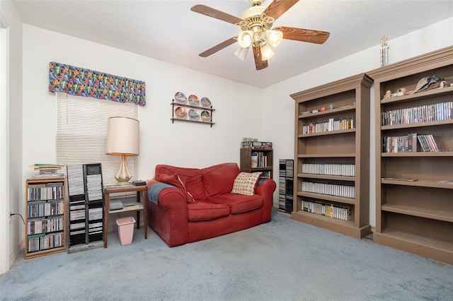 living area with ceiling fan and carpet