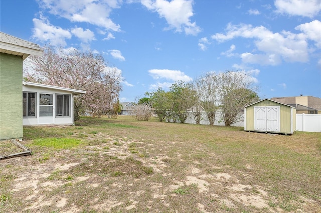 view of yard with an outbuilding, a storage unit, a fenced backyard, and a sunroom