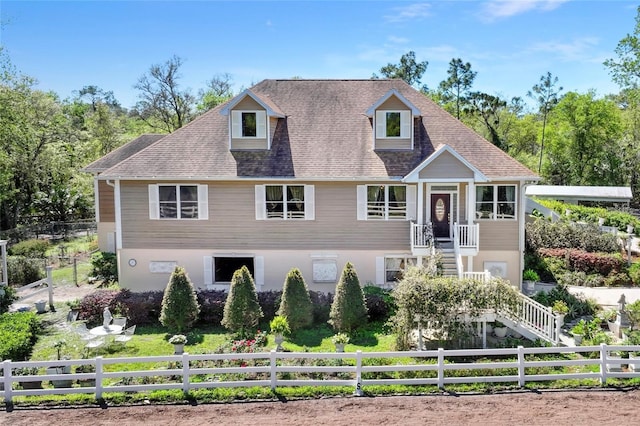 view of front of home featuring a fenced front yard, stairway, and roof with shingles
