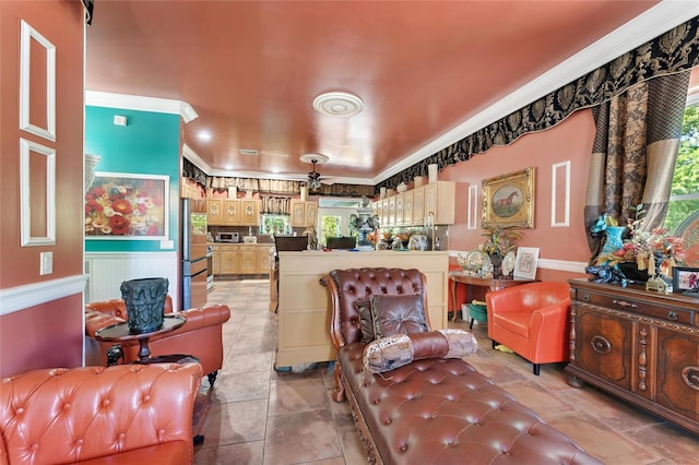 living room featuring light tile patterned floors, a ceiling fan, crown molding, and wainscoting