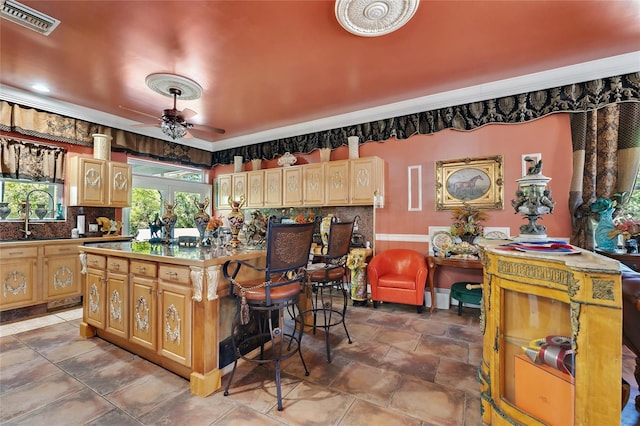 kitchen featuring backsplash, a kitchen island, a breakfast bar area, visible vents, and ceiling fan