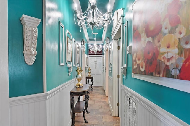 interior space with crown molding, wainscoting, visible vents, and a chandelier