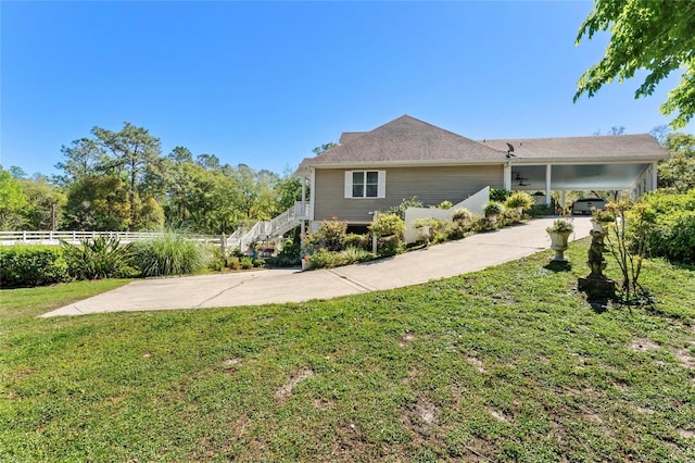view of side of property with concrete driveway, stairway, fence, an attached carport, and a lawn