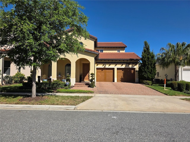15149 Canoe Pl, Winter Garden, FL 34787 - mediterranean / spanish-style house featuring a tile roof, decorative driveway, stucco siding, and an attached garage