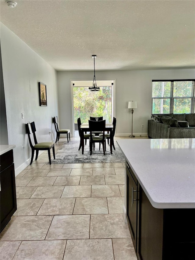 interior space with light tile patterned flooring, a textured ceiling, baseboards, and a wealth of natural light