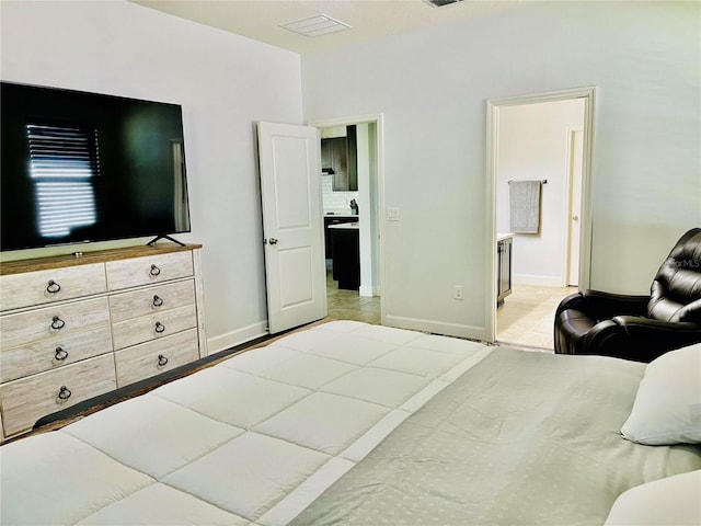 bedroom with connected bathroom, baseboards, and visible vents