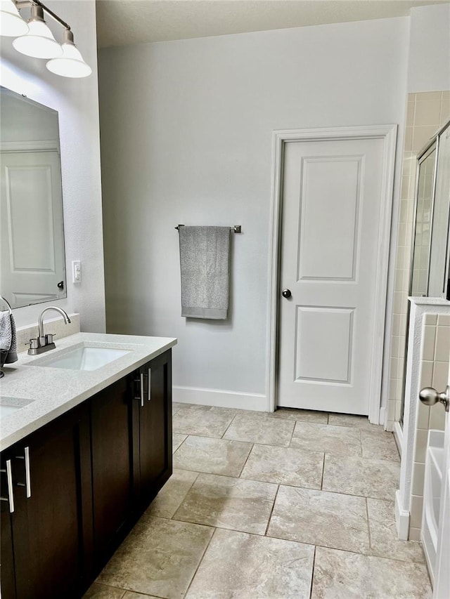 full bath featuring double vanity, a sink, baseboards, and a shower stall