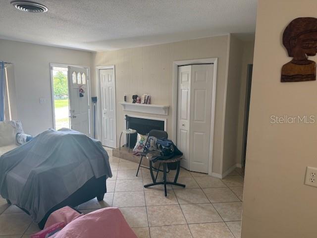 2108 Wolf Rd, Orlando, FL 32808 - bedroom featuring multiple closets, a textured ceiling, light tile patterned floors, and a fireplace