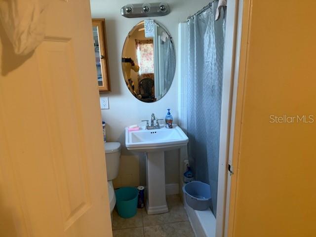 2108 Wolf Rd, Orlando, FL 32808 - full bath featuring tile patterned floors, a shower with shower curtain, toilet, and a sink