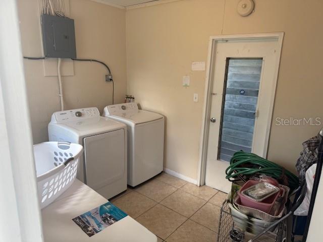 2108 Wolf Rd, Orlando, FL 32808 - laundry area with electric panel, washer and dryer, light tile patterned floors, and baseboards
