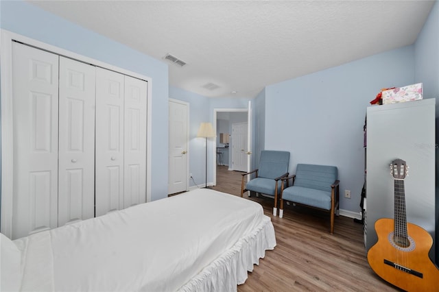654 Chadbury Way, Kissimmee, FL 34744 - bedroom featuring a closet, a textured ceiling, visible vents, baseboards, and wood finished floors