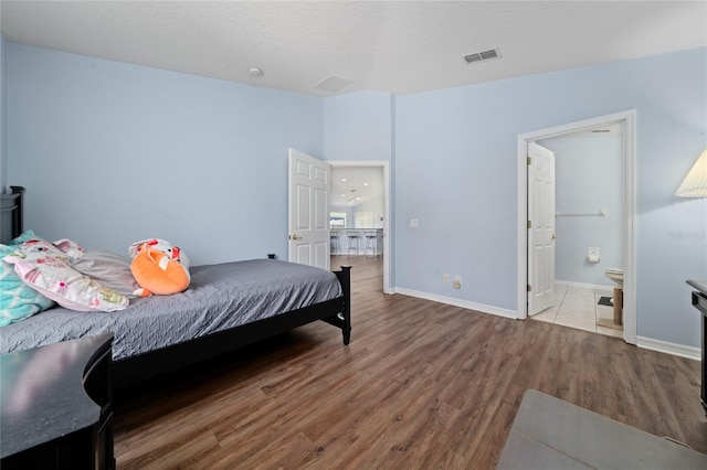654 Chadbury Way, Kissimmee, FL 34744 - bedroom featuring baseboards, connected bathroom, visible vents, and wood finished floors