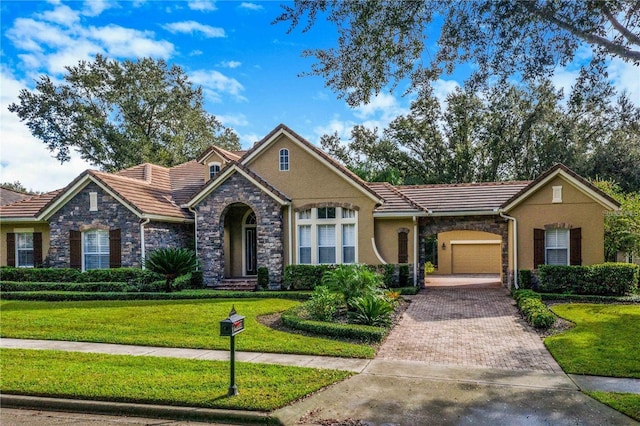 25813 Feather Ridge Ln, Sorrento, FL 32776 - view of front of home featuring stone siding, a tiled roof, a garage, decorative driveway, and a front lawn