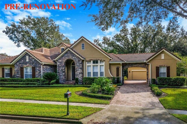 25813 Feather Ridge Ln, Sorrento, FL 32776 - view of front of house featuring stone siding, a tiled roof, an attached garage, decorative driveway, and a front yard