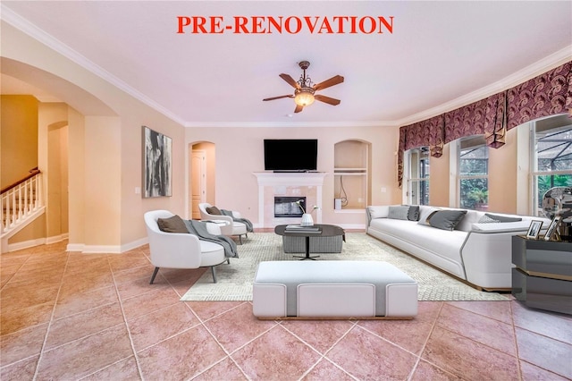 25813 Feather Ridge Ln, Sorrento, FL 32776 - living room featuring arched walkways, ornamental molding, a ceiling fan, a tiled fireplace, and tile patterned floors