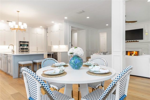 25813 Feather Ridge Ln, Sorrento, FL 32776 - dining space with a decorative wall, beverage cooler, ornamental molding, a chandelier, and light wood-style flooring
