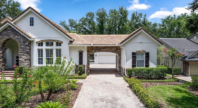 25813 Feather Ridge Ln, Sorrento, FL 32776 - view of front facade featuring stone siding, stucco siding, decorative driveway, an attached garage, and a tile roof