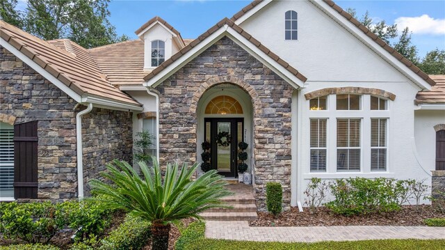 25813 Feather Ridge Ln, Sorrento, FL 32776 - view of exterior entry with stone siding, stucco siding, and a tile roof